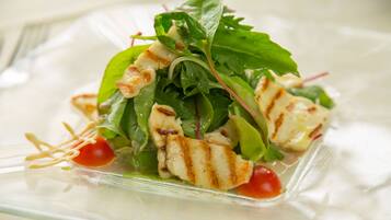 Ein Salat mit gegrilltem Hähnchen und Blattsalat auf einer transparenten Glasschale.
