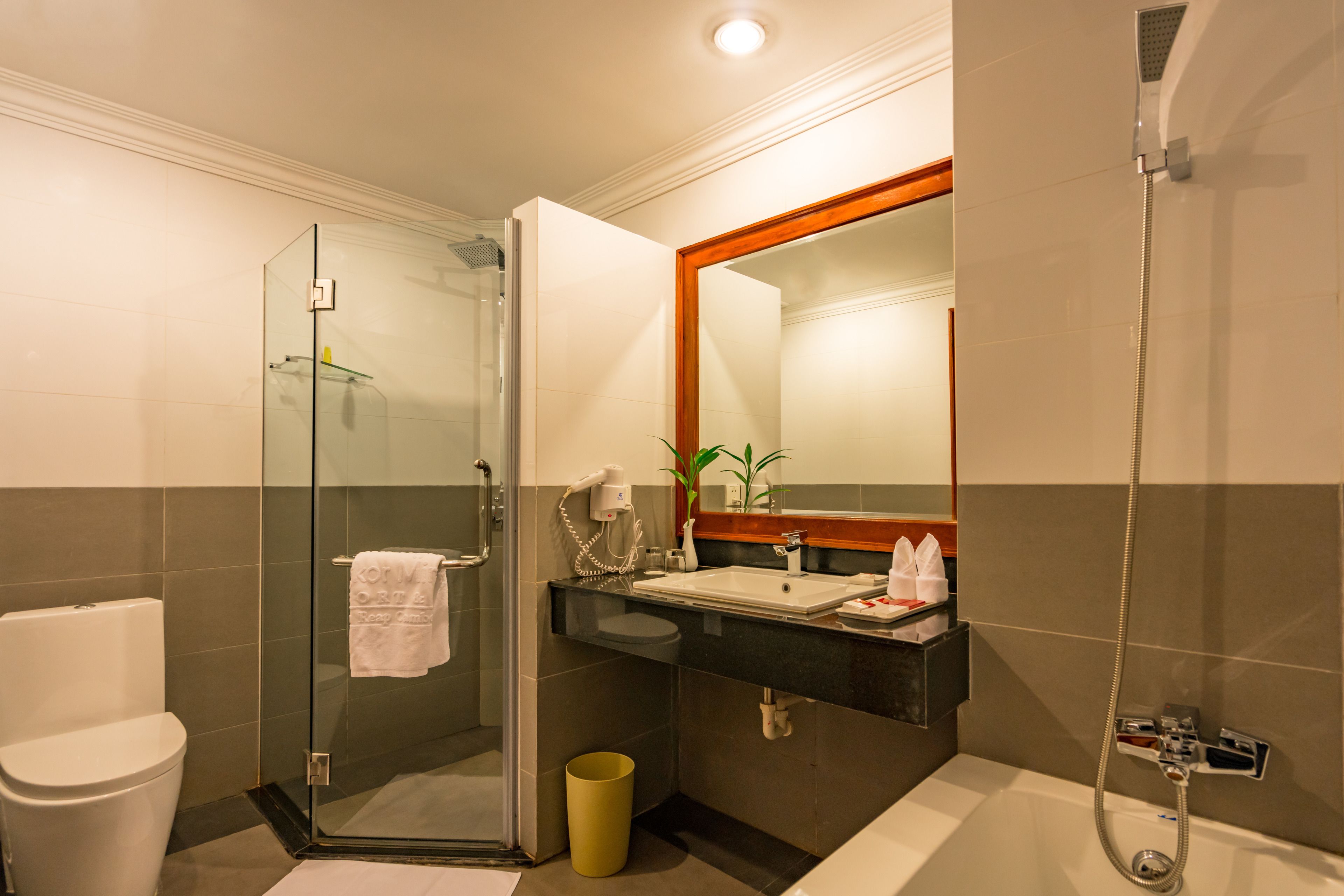 Un baño moderno con ducha de vidrio, un lavabo con espejo y un inodoro.
