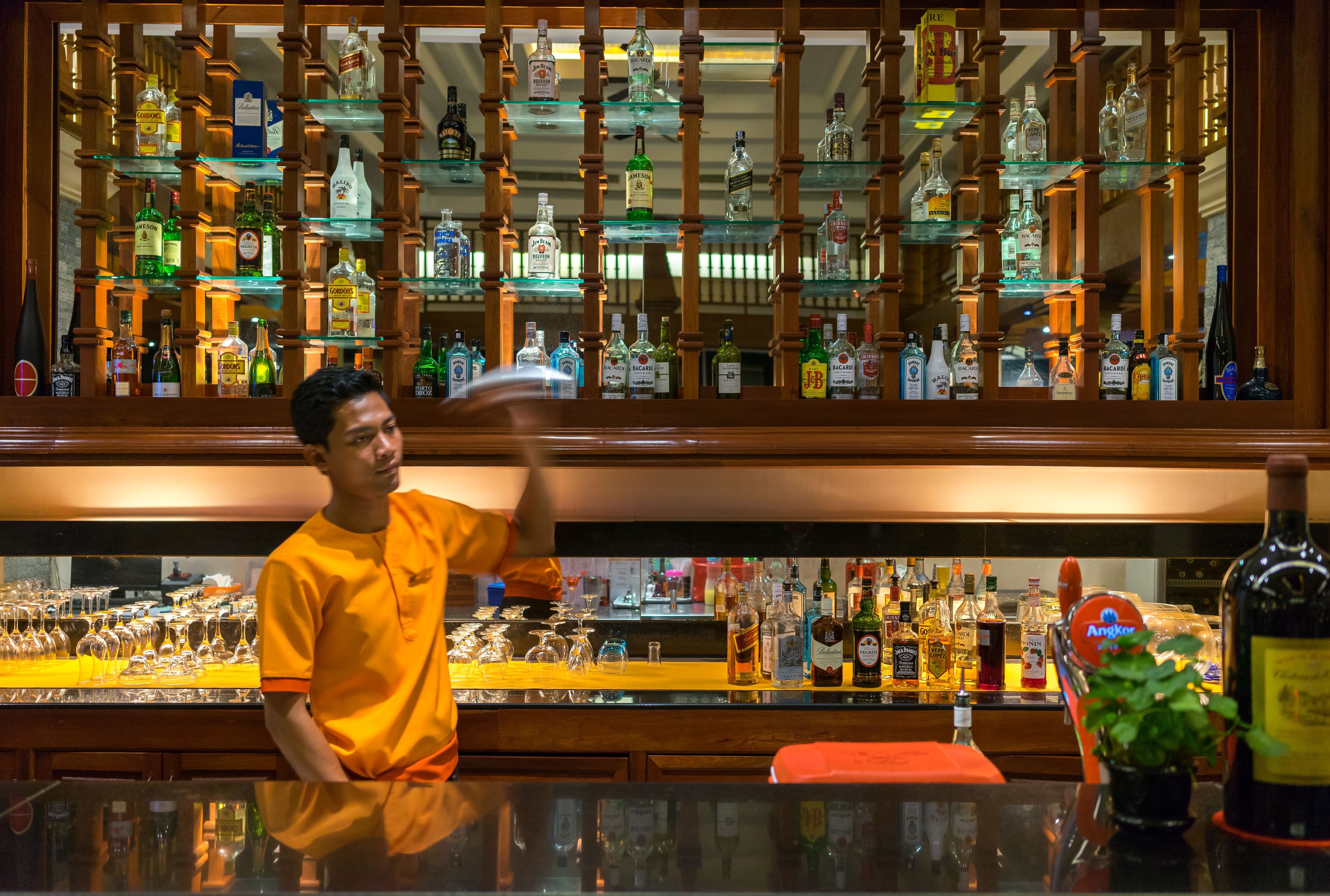Un bar con múltiples estantes llenos de botellas de licor y vasos.