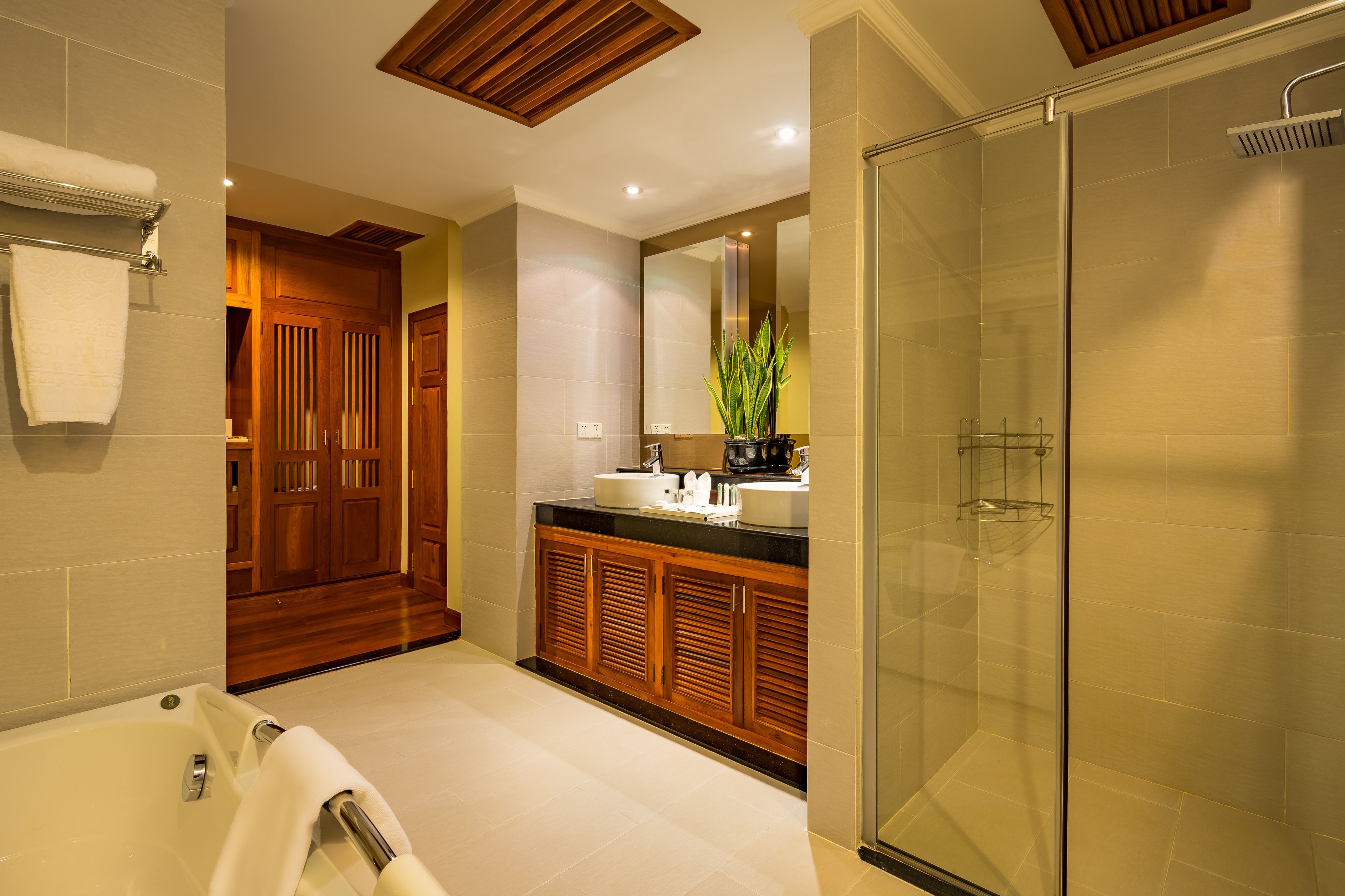 A modern bathroom with a glass-enclosed shower, a wooden vanity, and a bathtub.