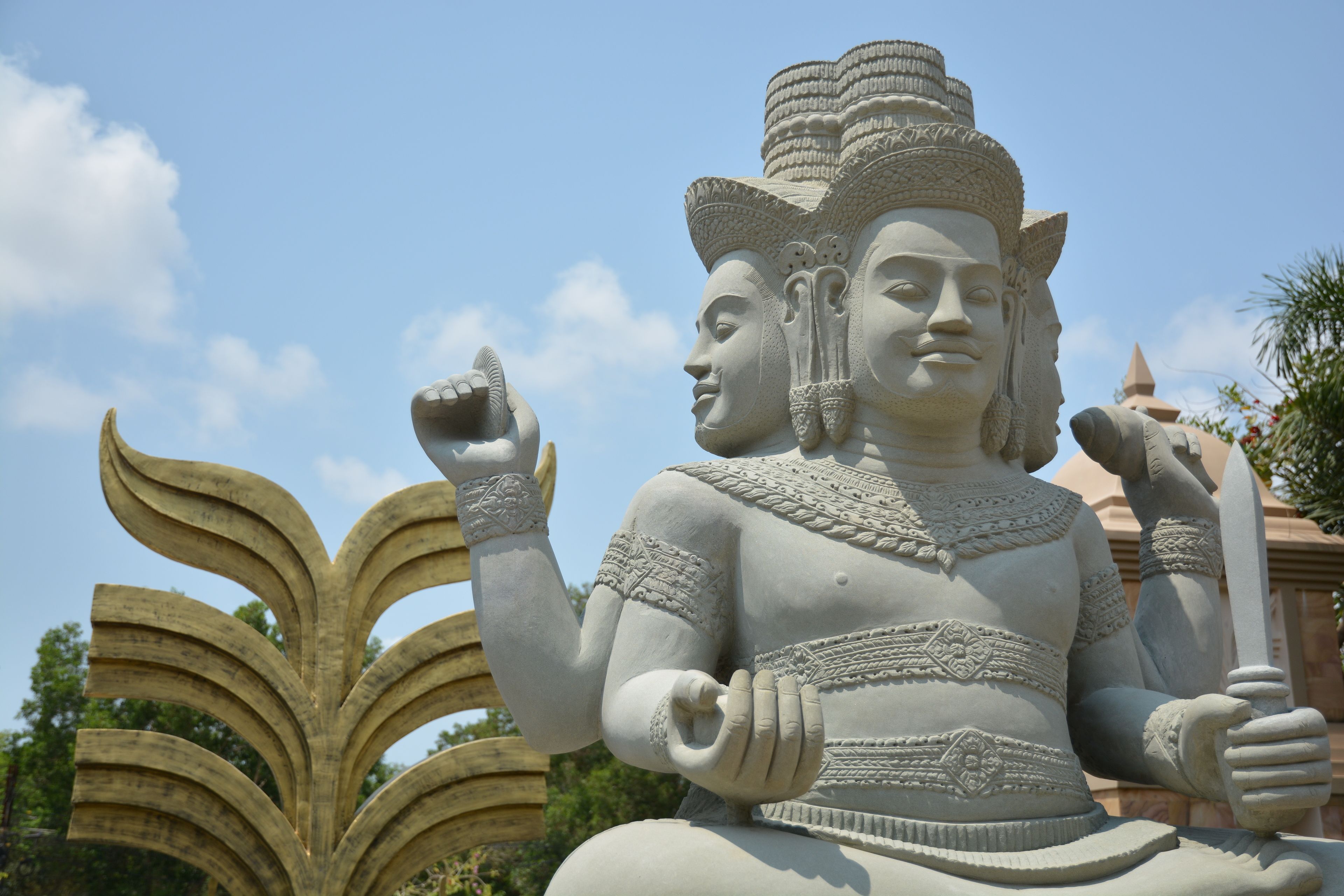 A large stone statue with intricate carvings, set against a clear sky.