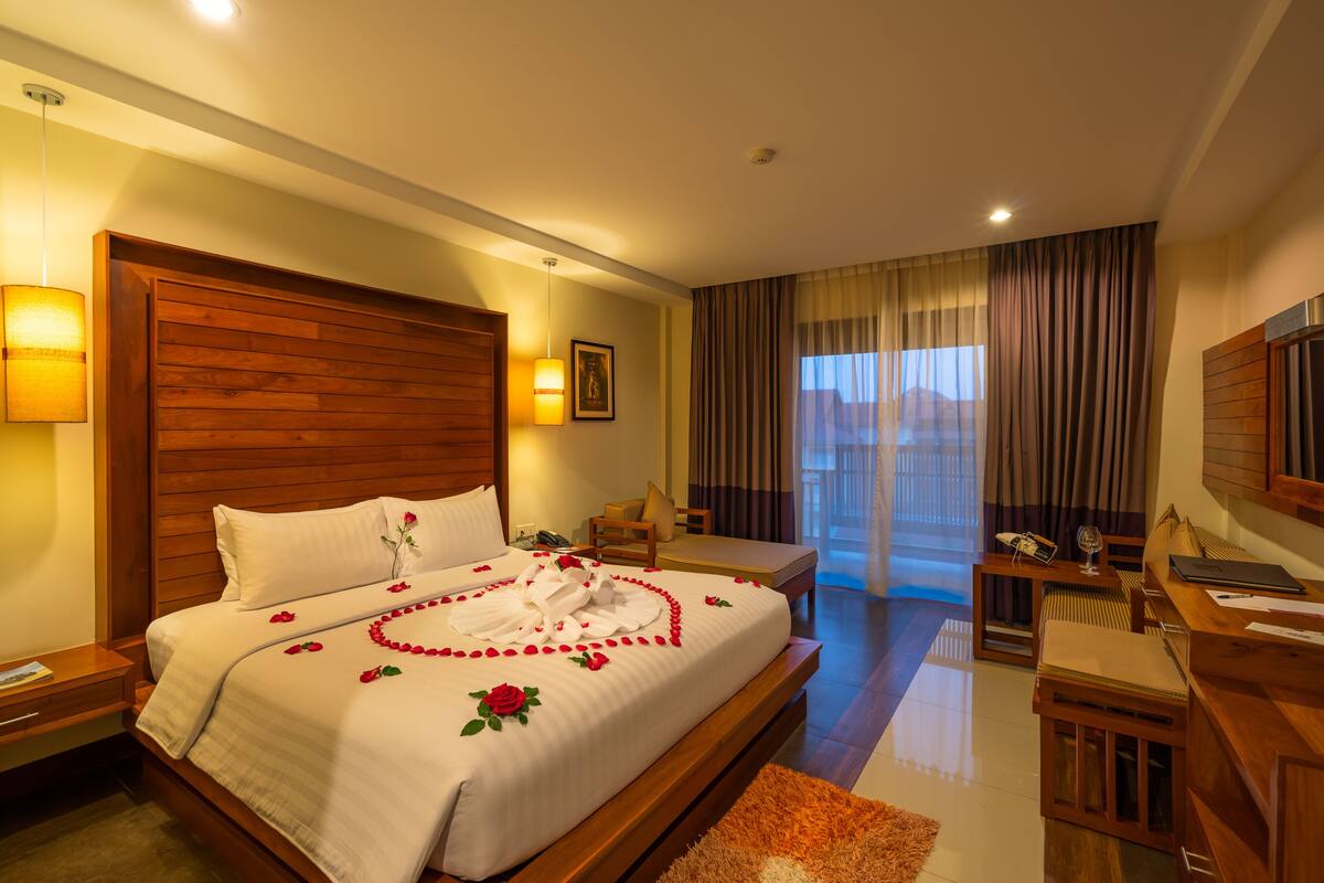 A hotel room with a large bed, a desk, and a view of the outdoors.