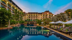 Un hotel con piscina, palmeras y sillas de descanso.