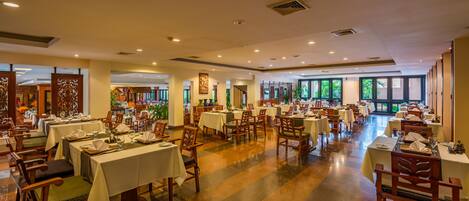 A spacious restaurant with multiple tables and chairs, large windows, and a polished floor.