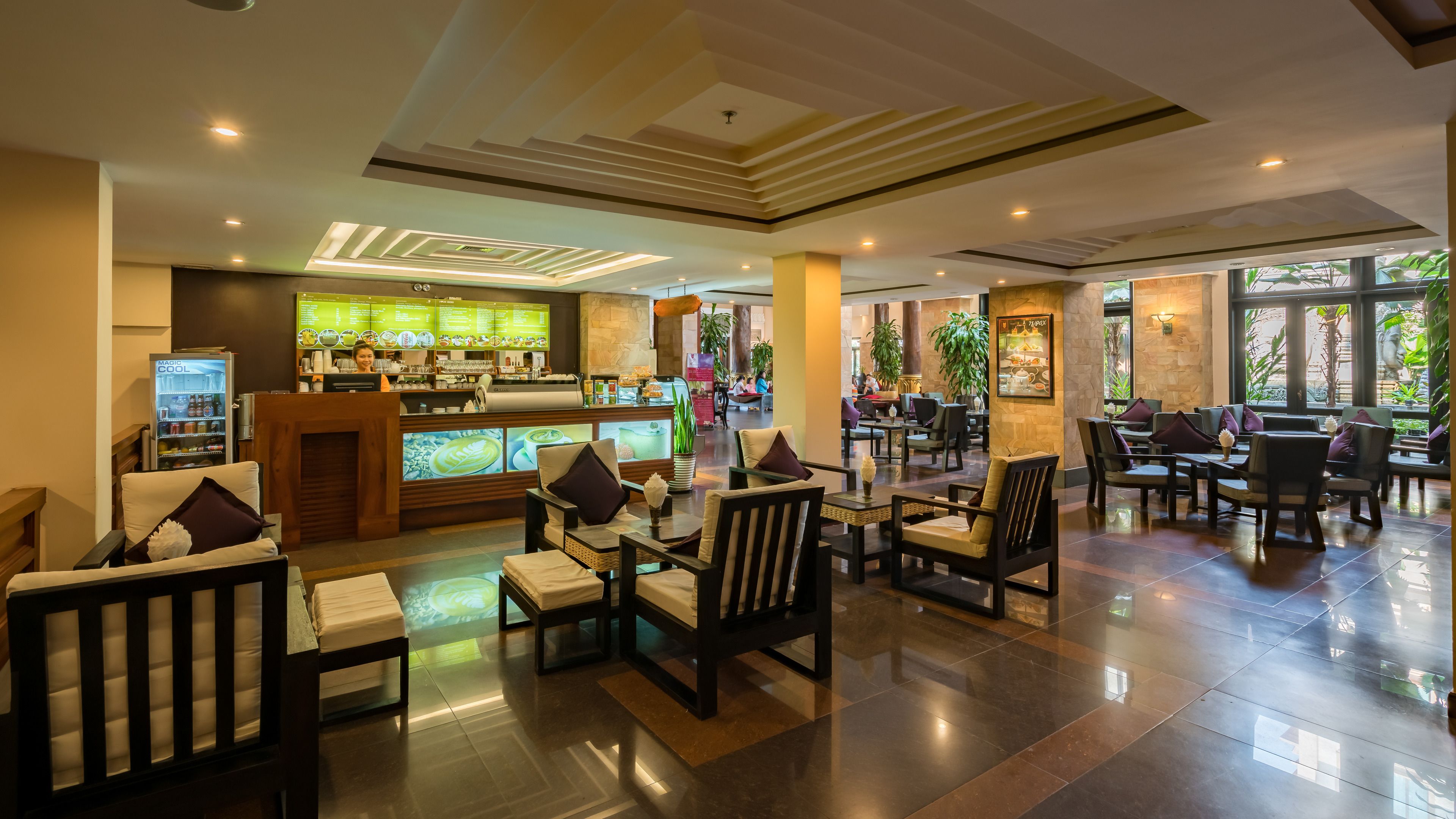 A spacious lobby with a coffee bar, seating area, and large windows offering a view of the outdoors.