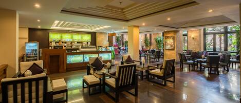 A spacious lobby with a coffee bar, seating area, and large windows offering a view of the outdoors.