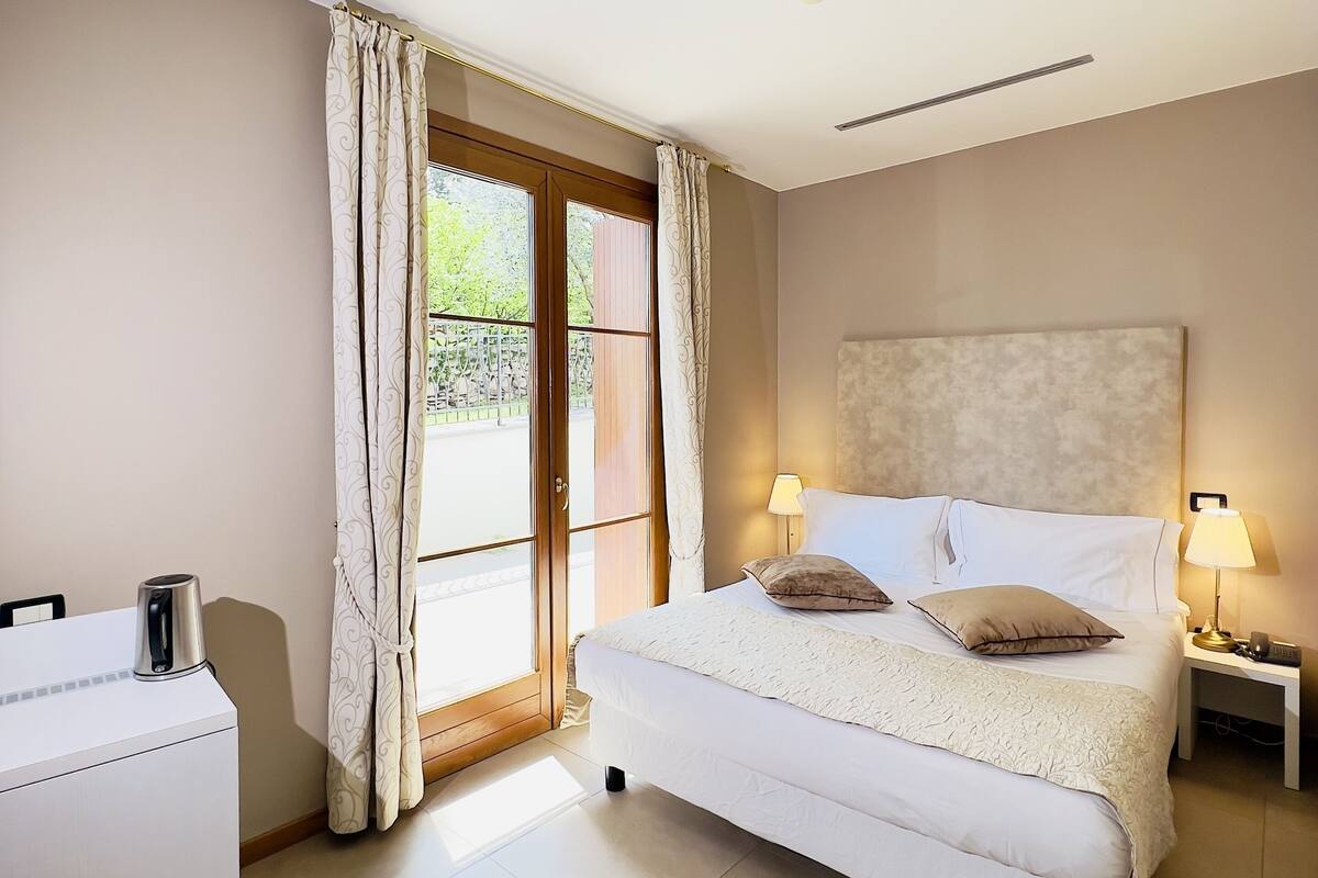 Une chambre à coucher avec un lit, des tables de chevet, un bureau et une fenêtre avec des rideaux.