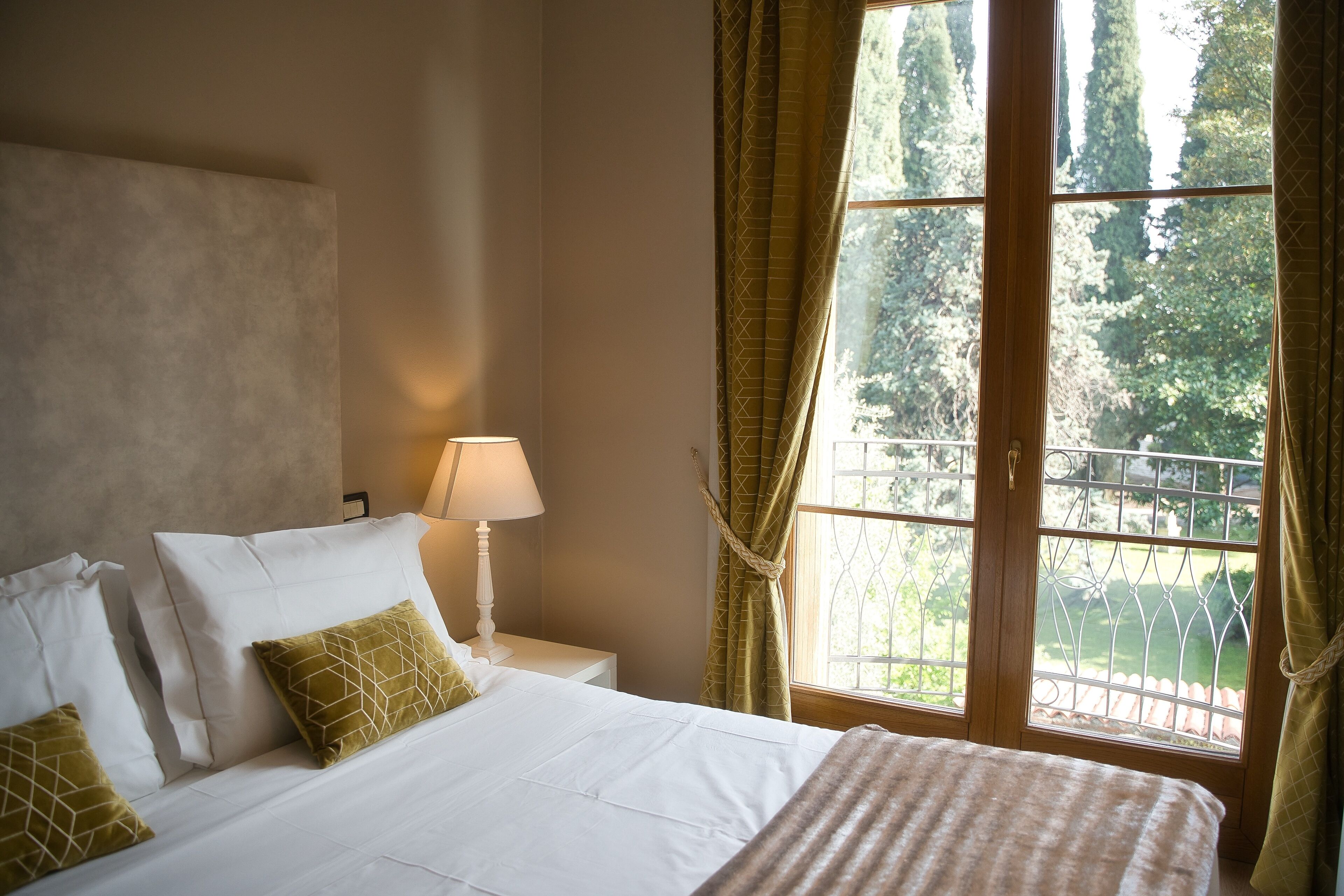 A bedroom with a bed, nightstand, lamp, and a window with curtains.