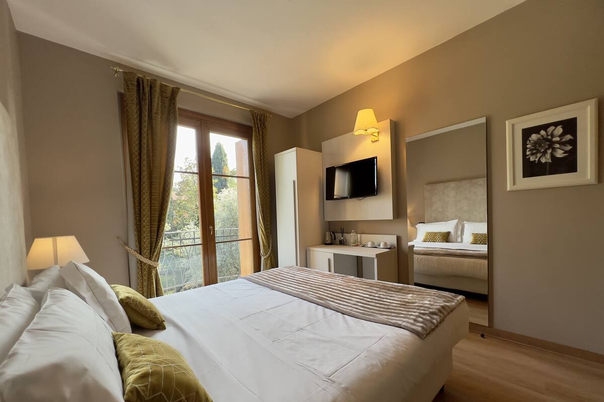 Une chambre d’hôtel comprenant un lit, une table de chevet, une lampe, une télévision et un bureau avec une chaise.