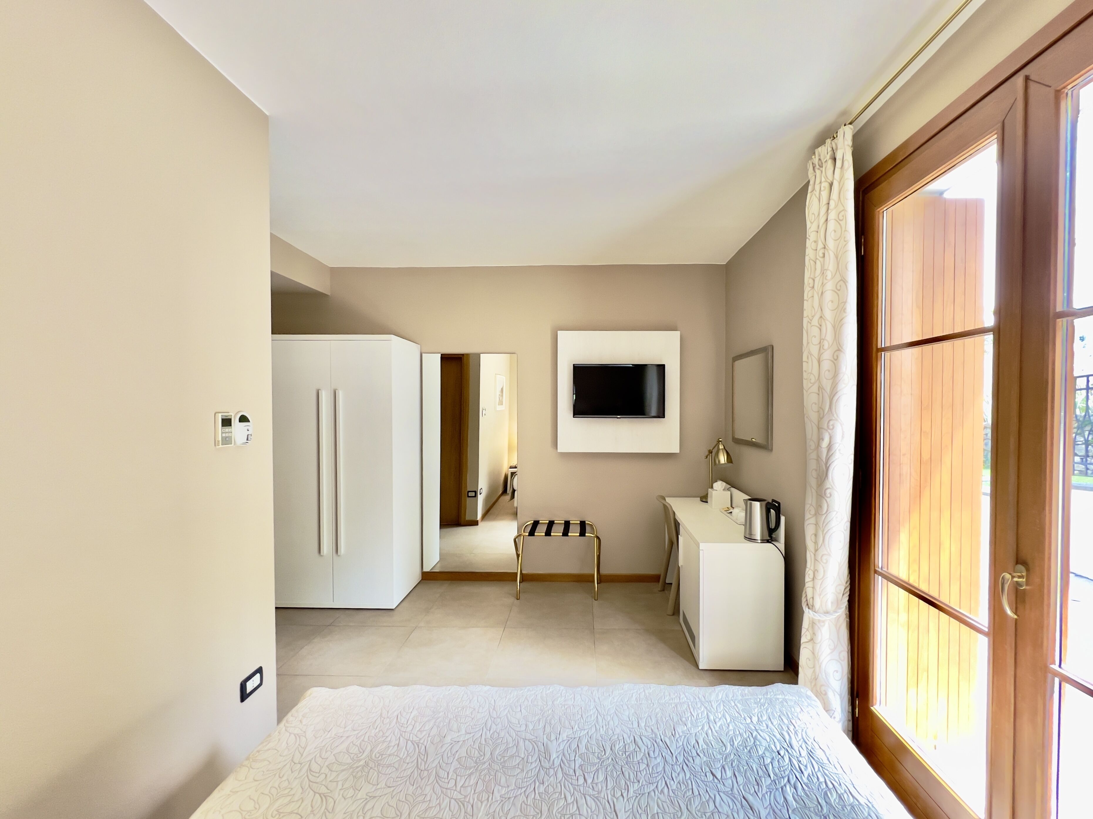 Une chambre à coucher avec un lit, un bureau, une télévision et une armoire.