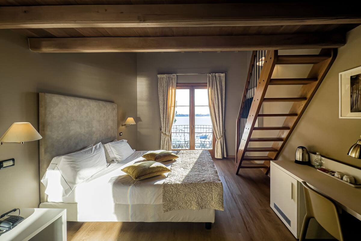 Une chambre à coucher avec un lit, des lampes de chevet, un bureau et une fenêtre avec des rideaux.