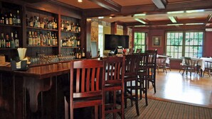 A bar area with wooden furniture, shelves with bottles, and a television. - Lumberville 1740 House (New Hope)