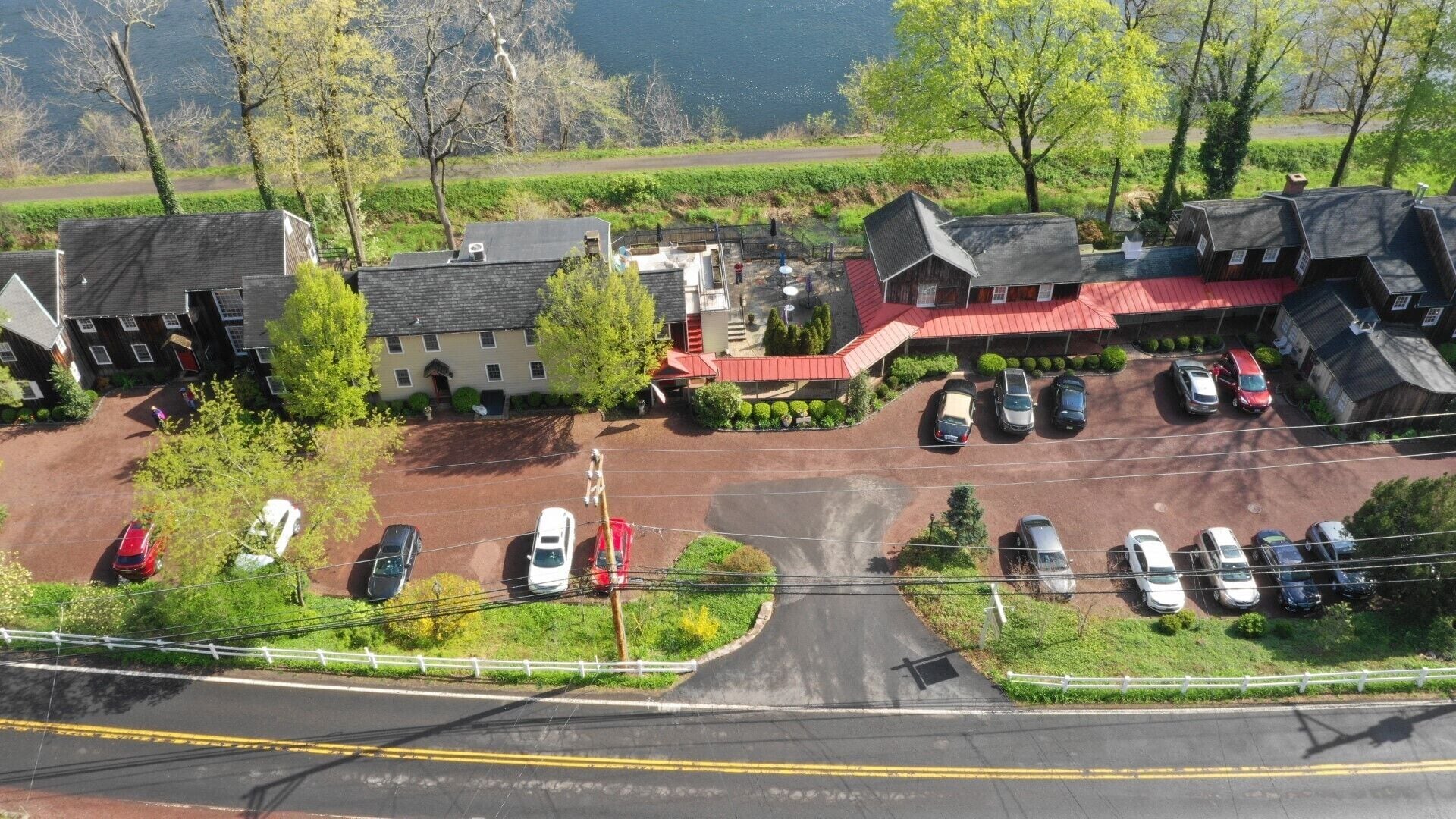 An aerial view of a rural area with a parking lot, several buildings, and a road.