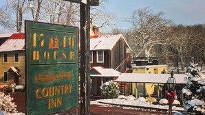 A green sign for a country inn with a rustic building in the background. - Lumberville 1740 House (New Hope)