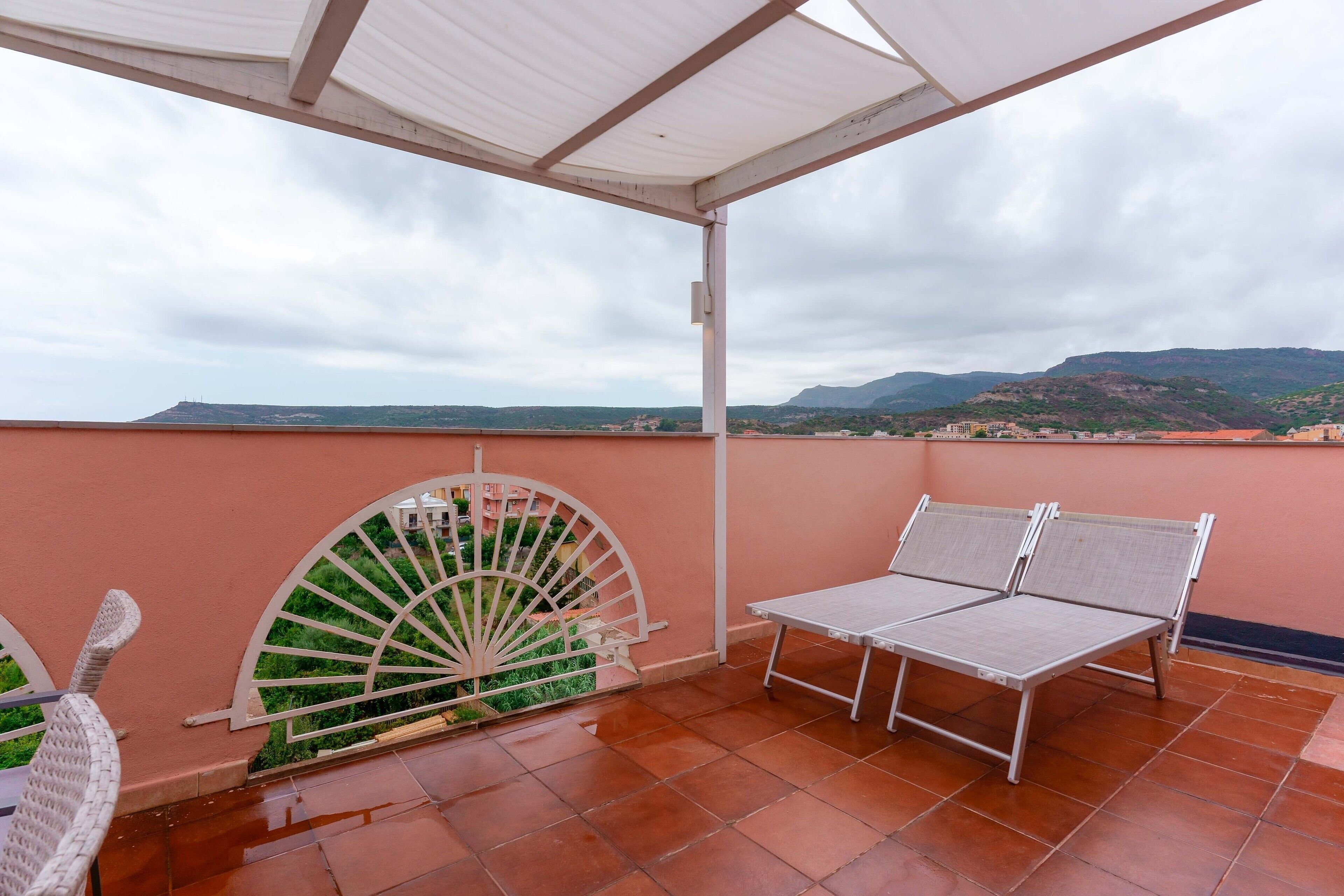 A terrace with a view of distant hills, a white chair, and a table.
