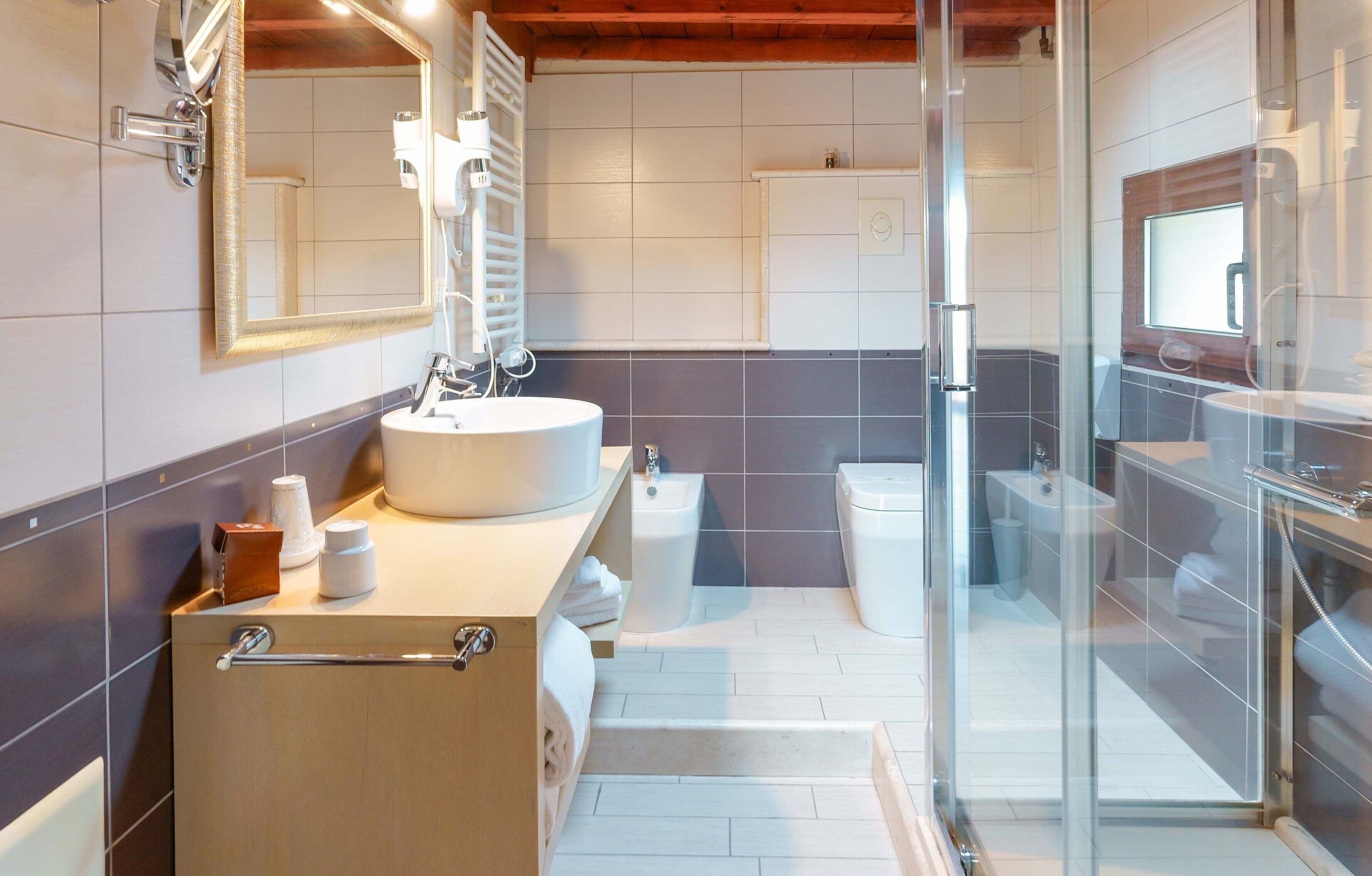 A modern bathroom with a large sink, mirror, and glass shower enclosure.