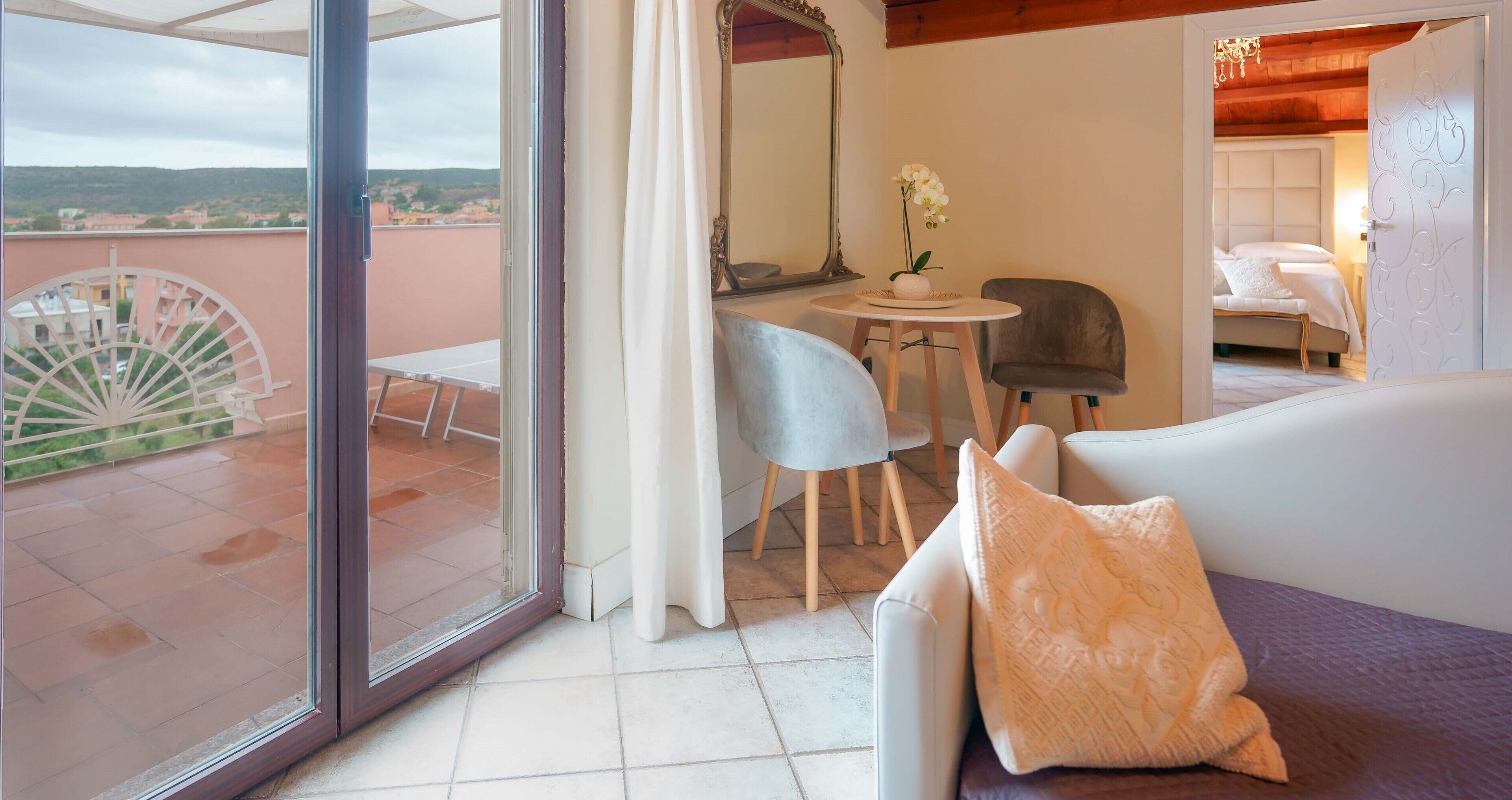 Habitación de hotel con balcón, zona de comedor y cama.