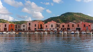 Un muelle con barcos amarrados y edificios de colores pastel.