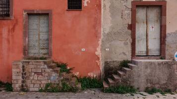 Un bâtiment à la façade rouge, avec une petite fenêtre et une statue sur le côté droit.