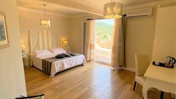 A bedroom with a bed, bedside tables, a hanging light fixture, a chair, and a view of the outdoors.