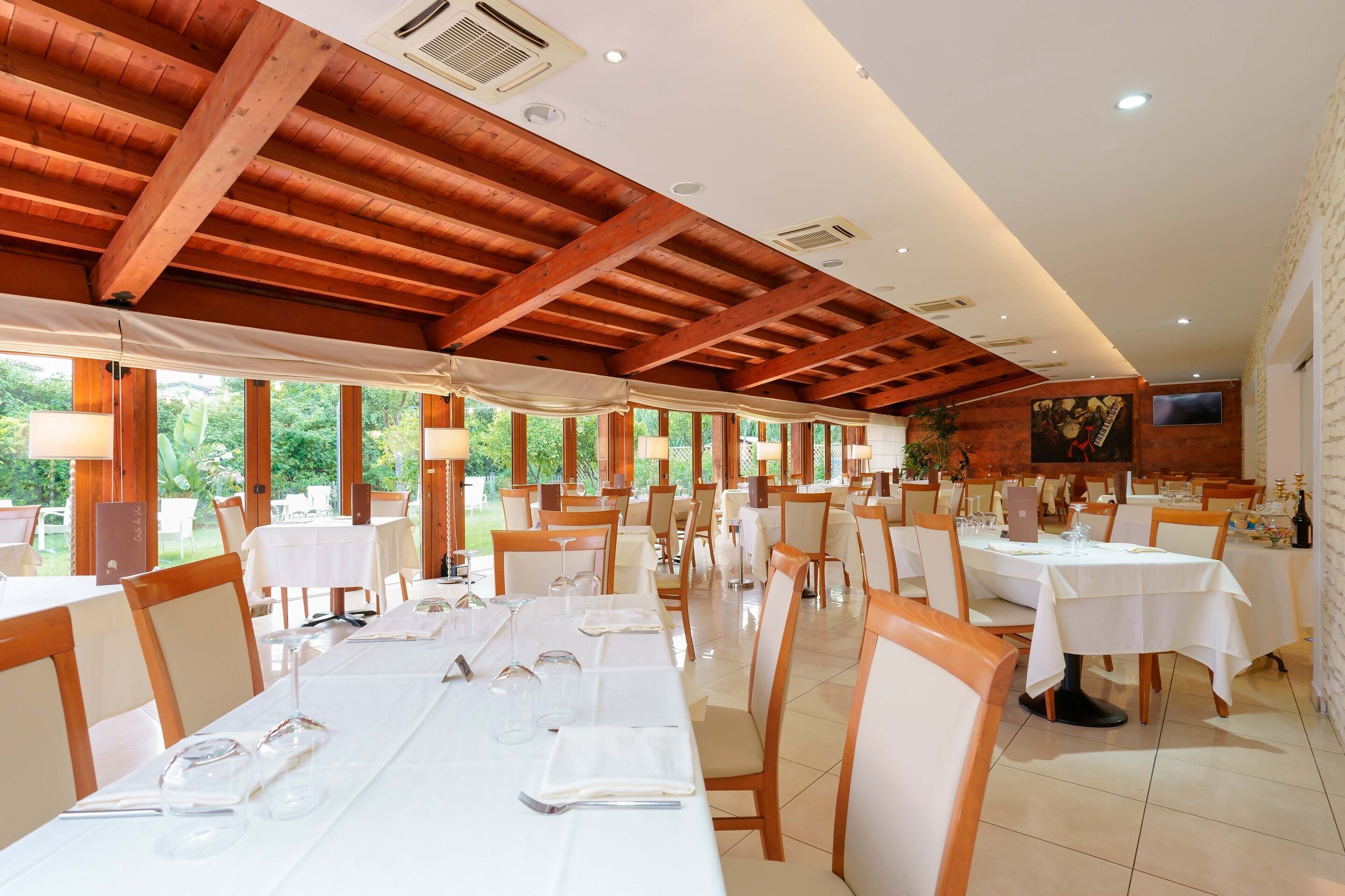 Un restaurant avec des poutres en bois, des tables et des chaises blanches.