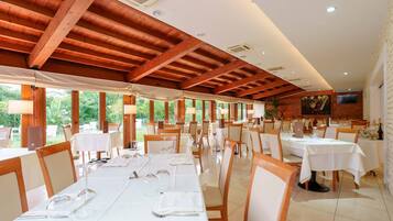 Un restaurante con vigas de madera, mesas y sillas blancas.