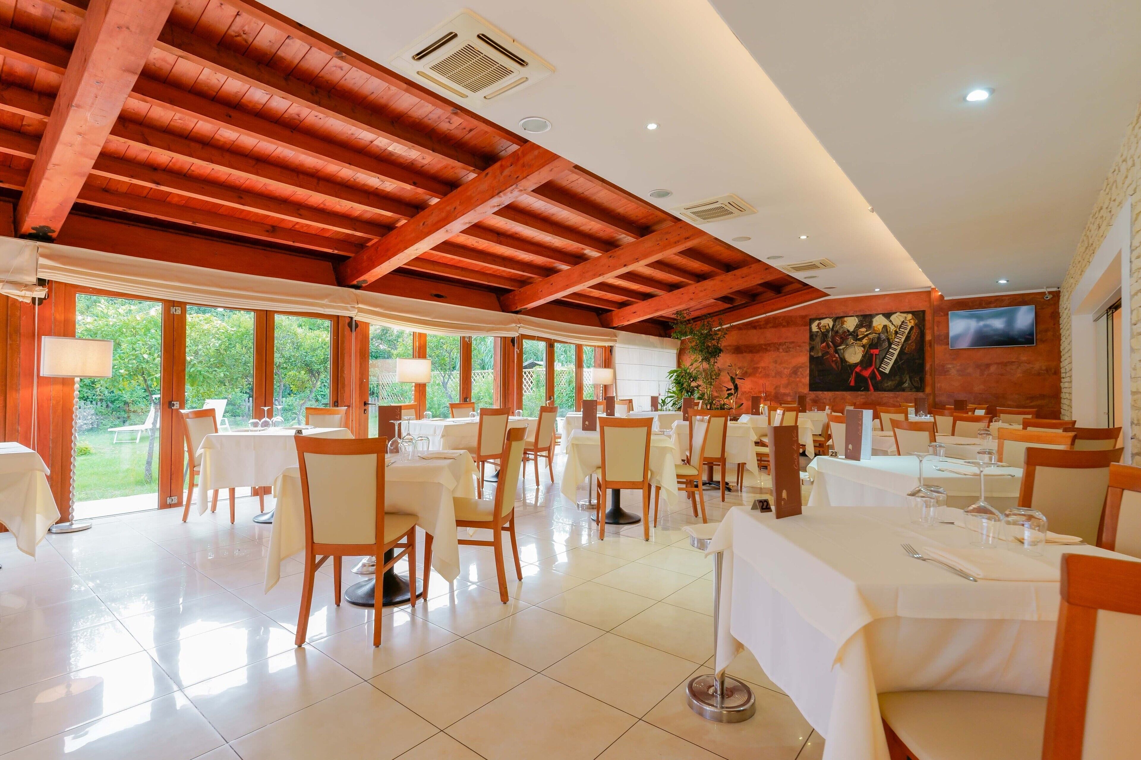 A spacious dining area with high ceilings and large windows, featuring neatly arranged tables and chairs.