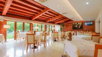 A spacious dining area with high ceilings and large windows, featuring neatly arranged tables and chairs.
