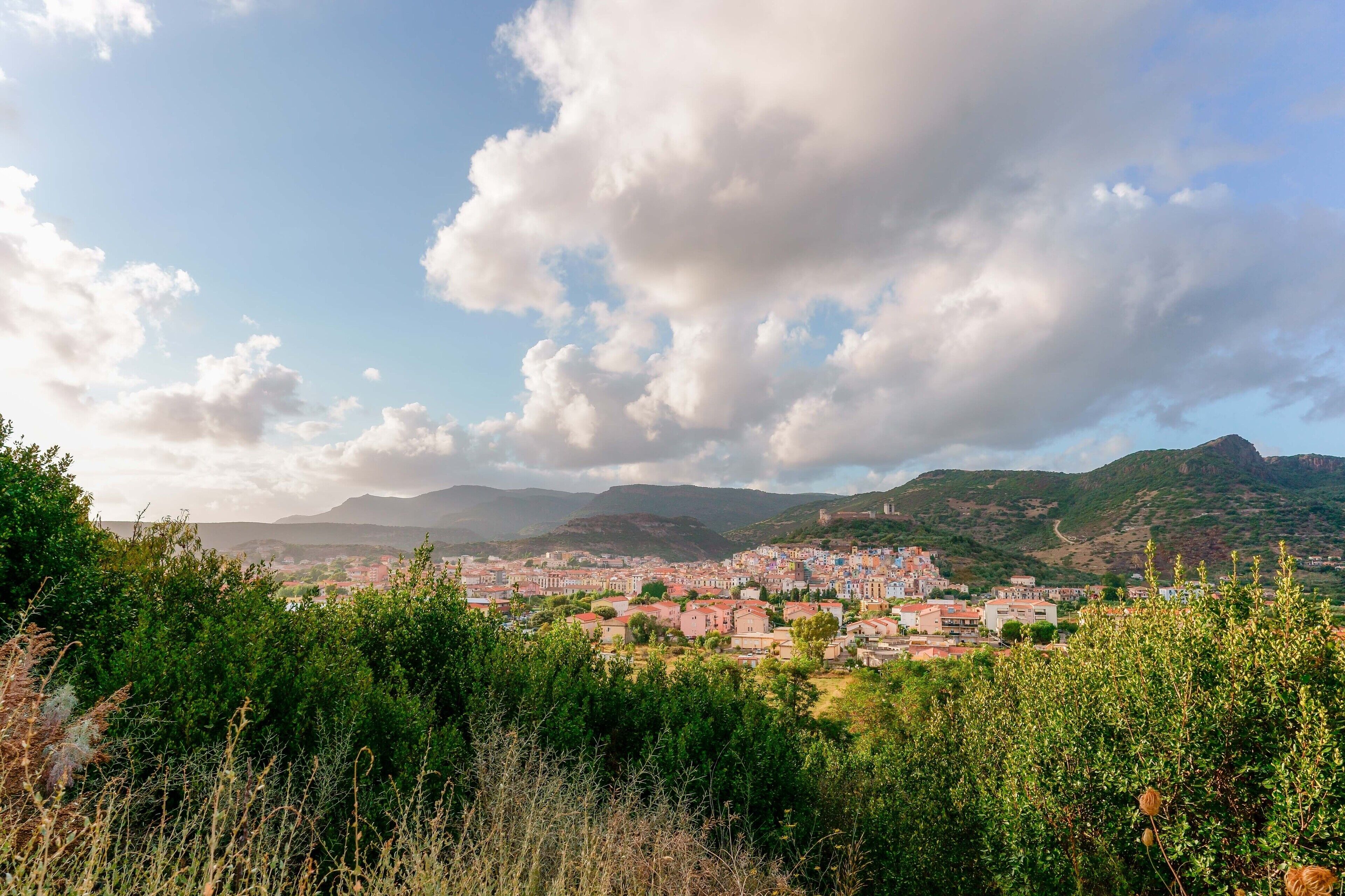 Une ville où se côtoient des bâtiments traditionnels et modernes, entourée de verdure et de montagnes.