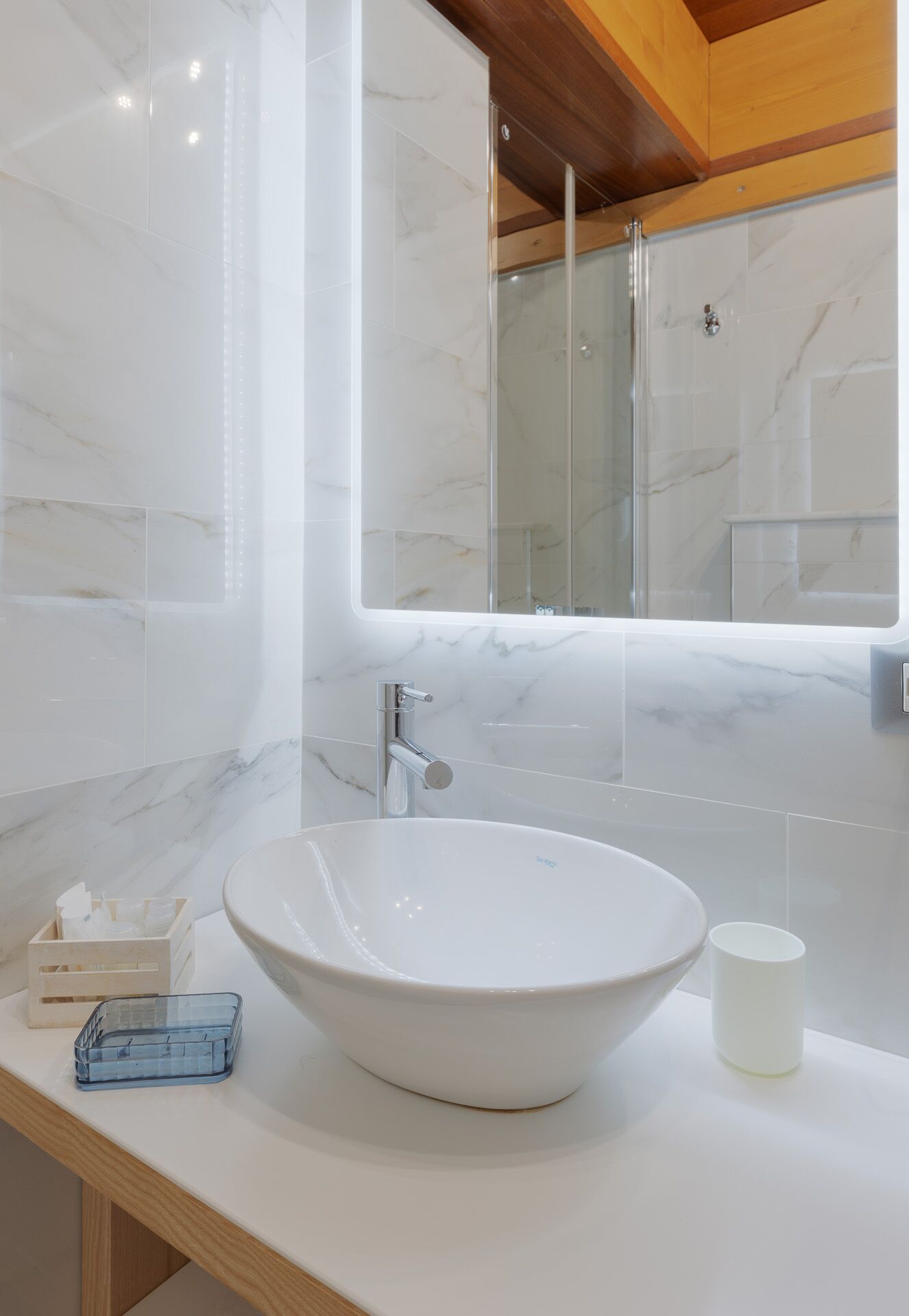 Een badkamer met een grote witte wastafel, een spiegel en een houten plafond.