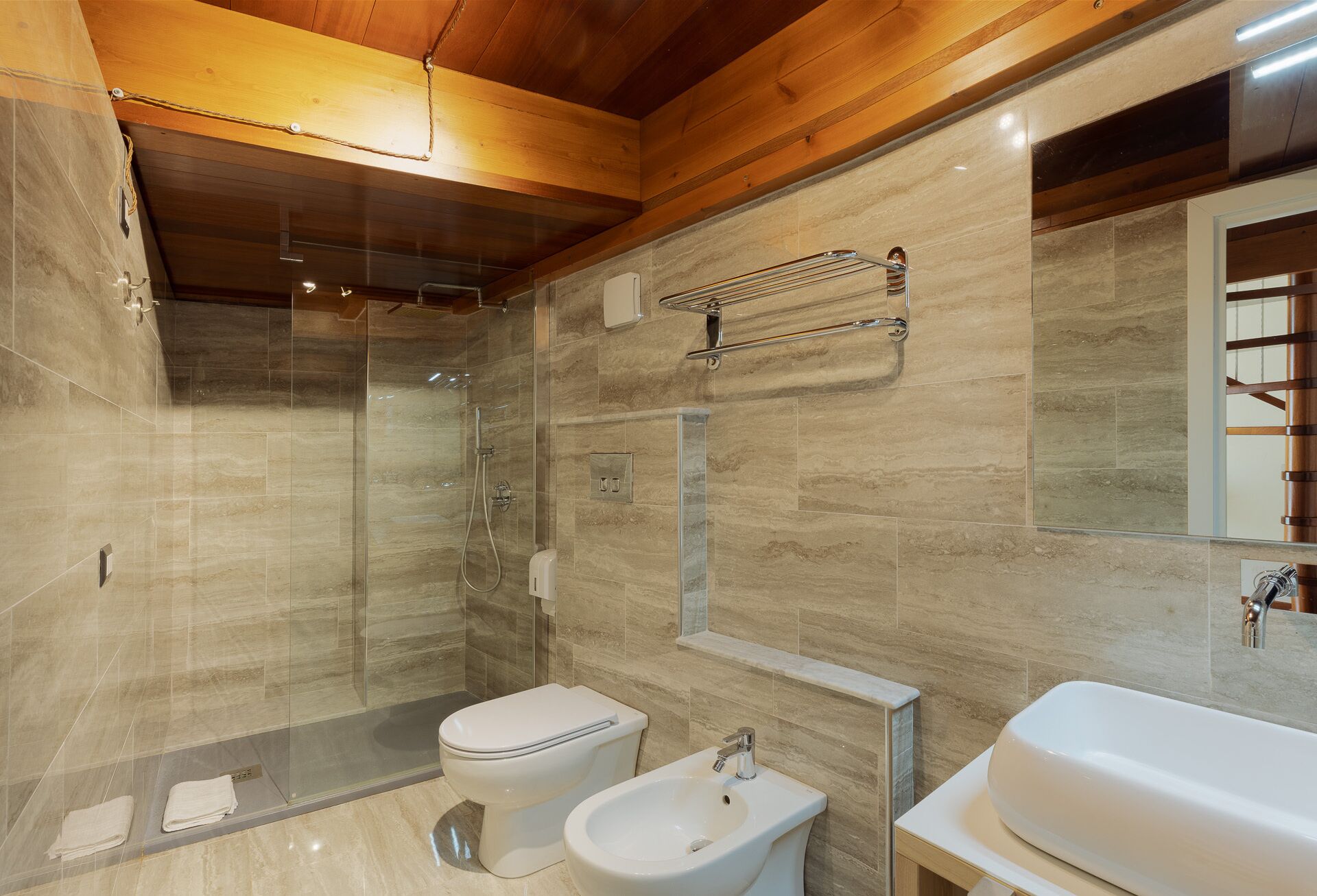 Un bagno moderno con doccia vetrata, un water, un bidet e un lavandino.