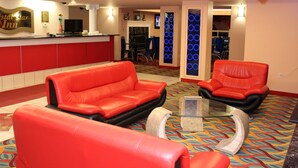 A hotel lobby with red leather sofas, a glass coffee table, and a reception area with a TV and a sign reading "Crystal Star Inn". - Crystal Star Inn Edmonton Airport (Leduc)