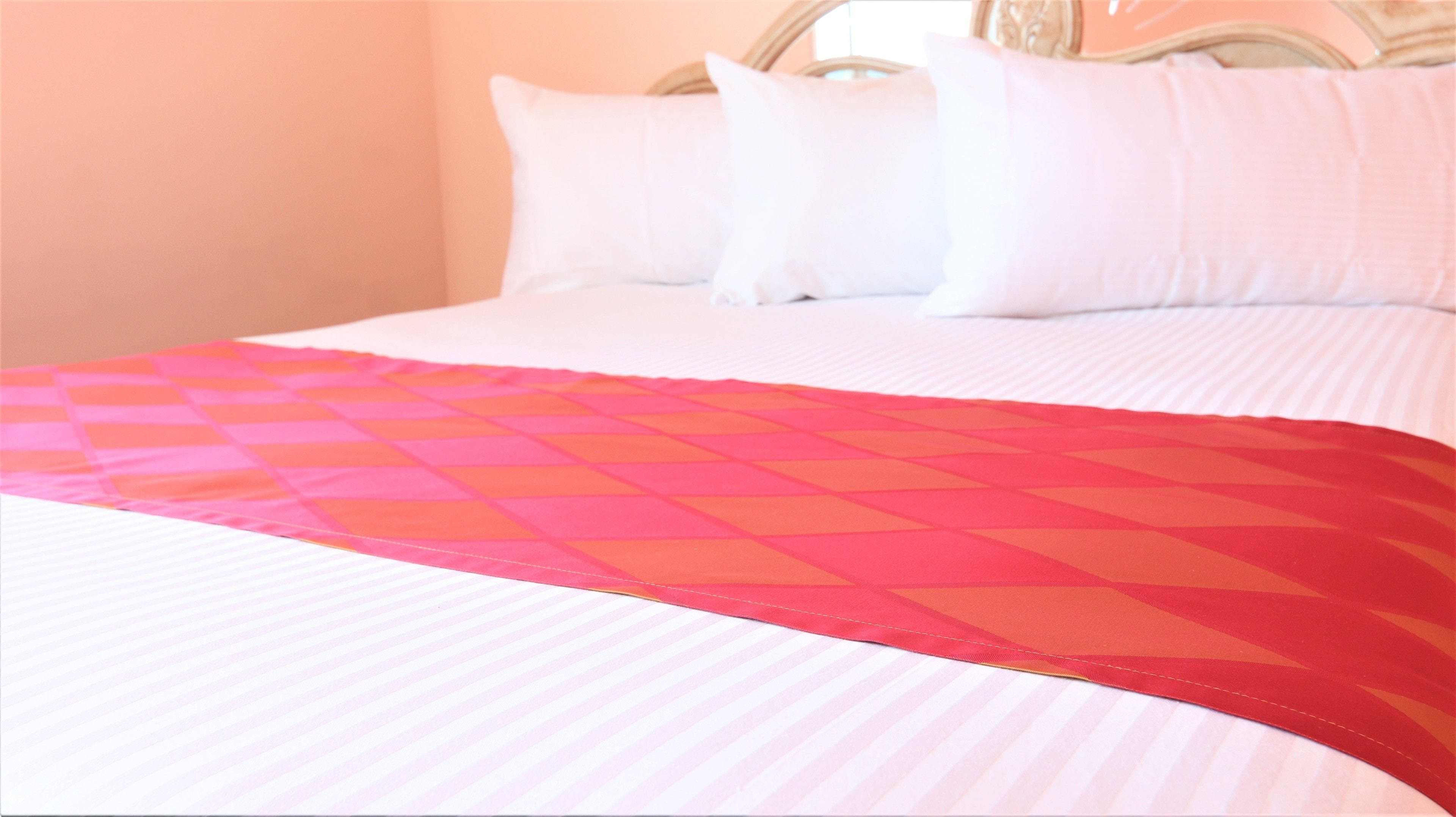 A bed with a patterned bedspread and white pillows.