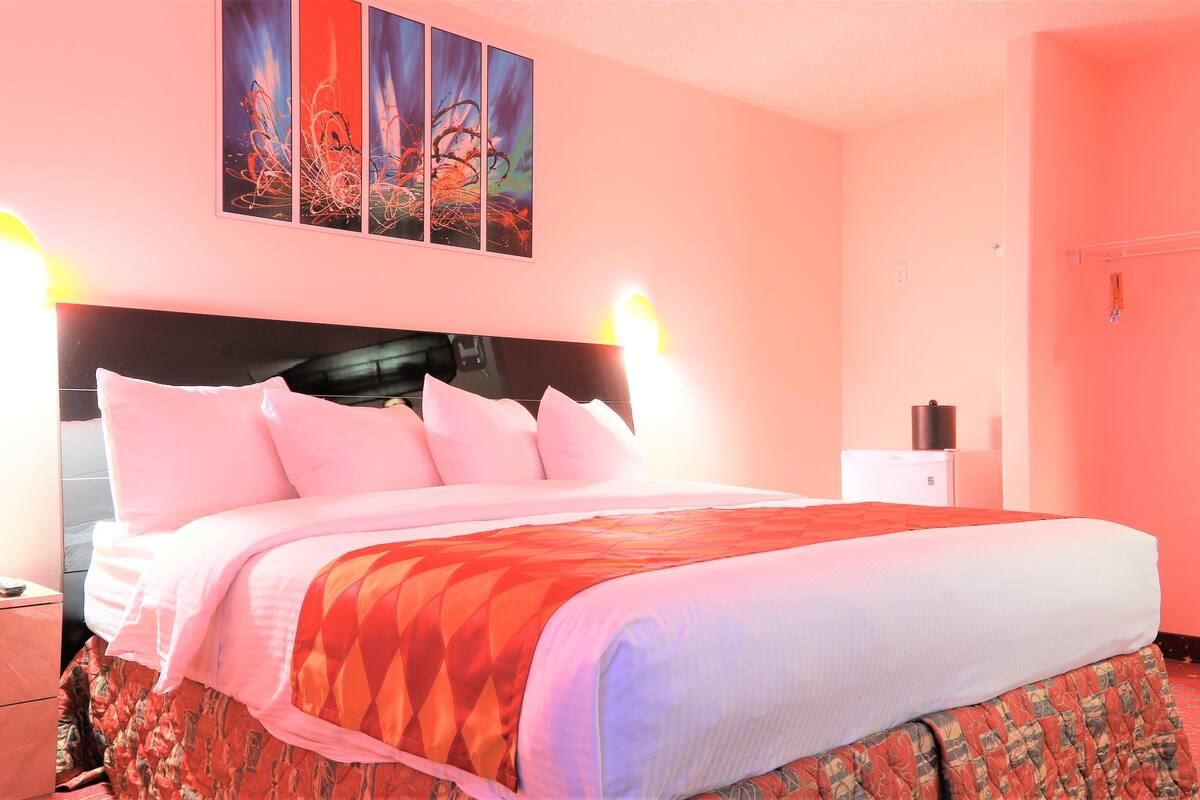 Habitación de hotel con una cama grande, una mesita de noche, un aparador y una obra de arte colgada en la pared.