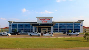 A Crystal Star Inn building with a large sign, multiple parked cars, and a grassy area in front.