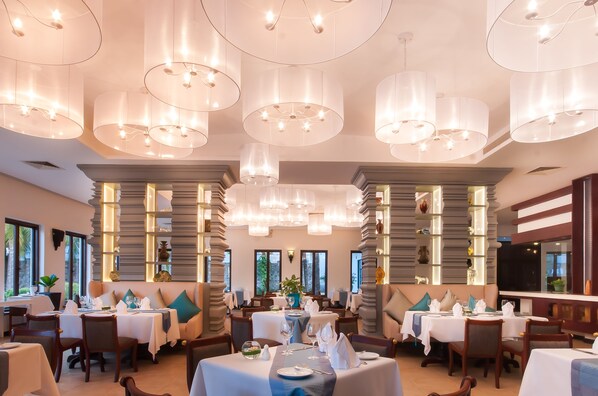 A restaurant with multiple tables, elegant chandeliers, and a modern interior design. - Lotus Blanc Resort (Siem Reap)