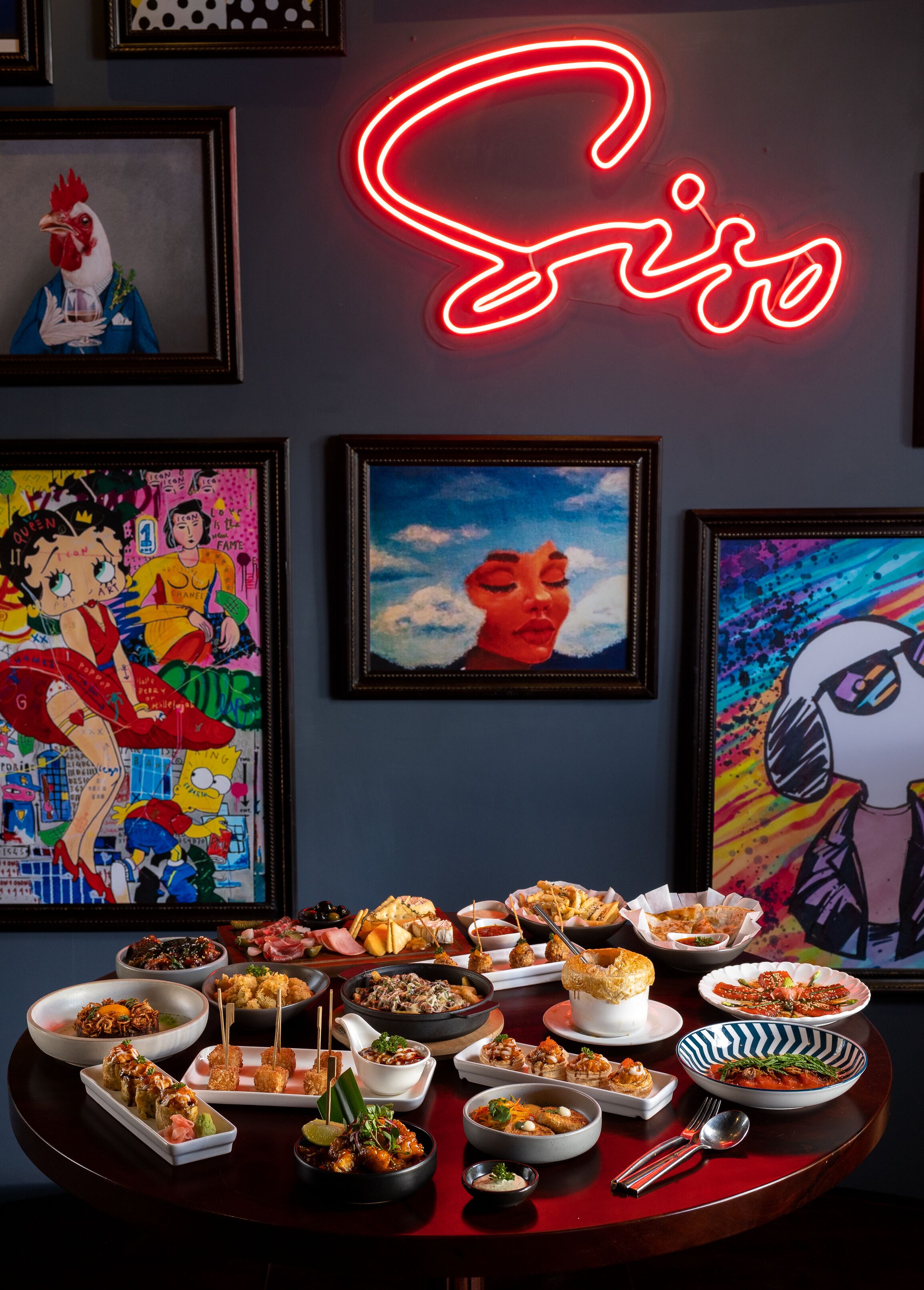 A table with various dishes and a neon sign above.