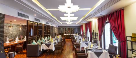 A restaurant with a long dining area, multiple tables, and a modern ceiling design.