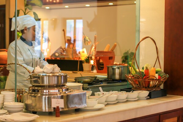 A buffet setup with various dishes and a chef preparing food.