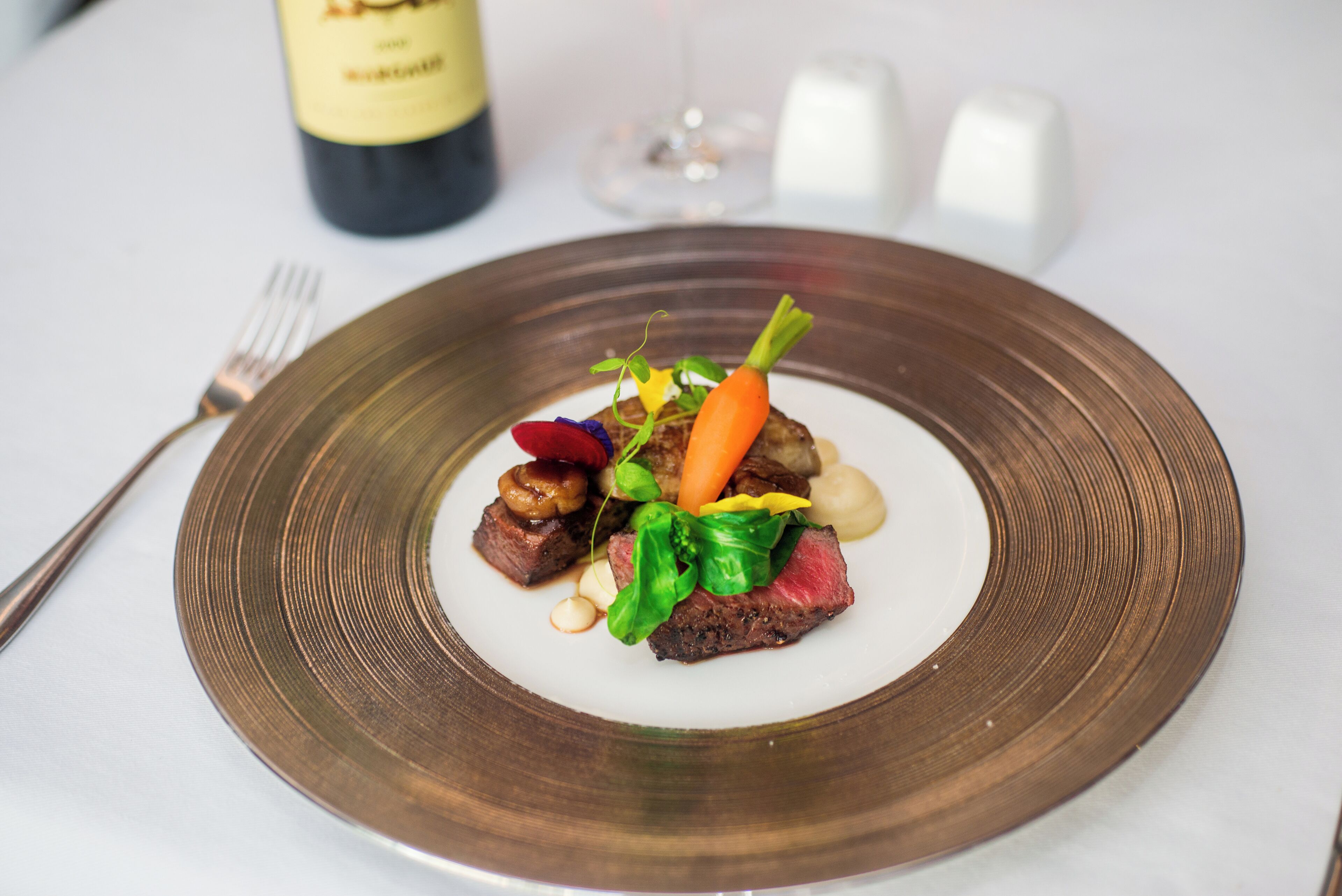A plated dish with steak, vegetables, and mushrooms.
