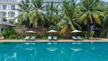 Een buitenzwembad, parasols bij het zwembad en ligstoelen