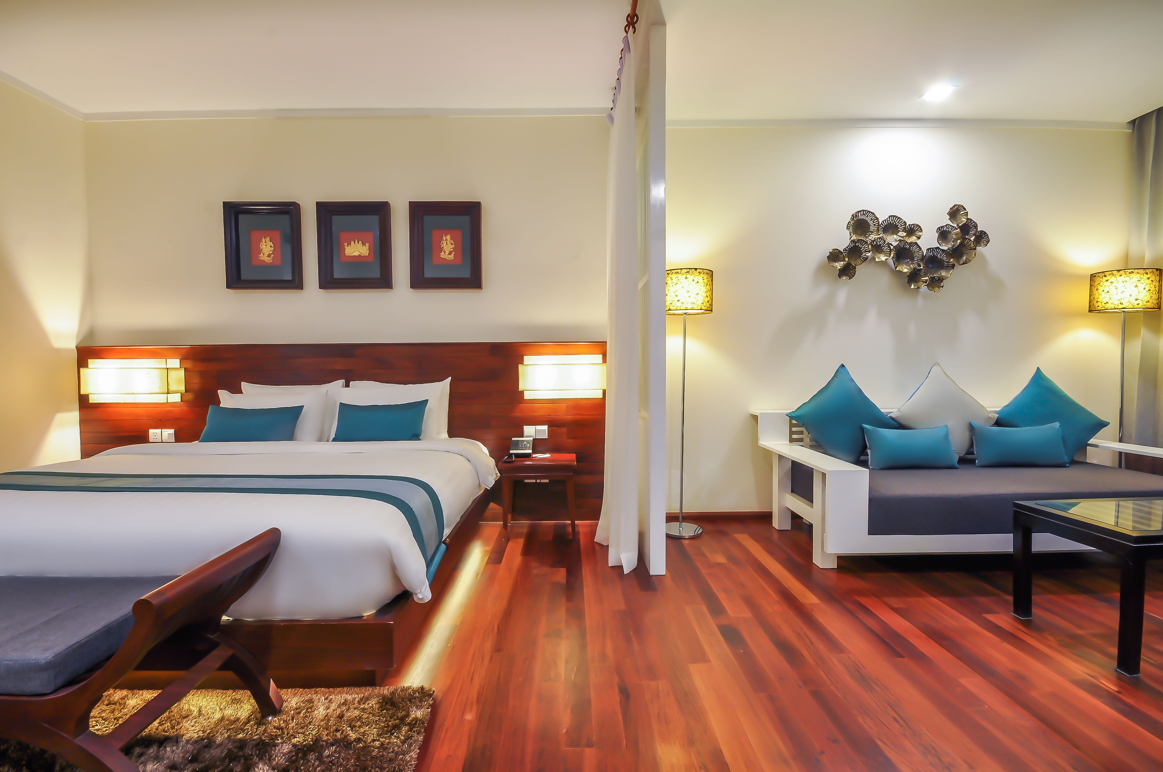 A hotel room with a bed, a sofa, a nightstand, and a lamp.