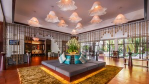 A spacious lobby with a large seating area, decorative hanging lamps, and a view of the outdoors. - Lotus Blanc Resort (Siem Reap)