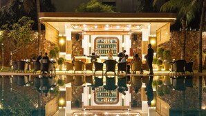 An outdoor bar area with a pool reflecting the bar and guests. - Lotus Blanc Resort (Siem Reap)