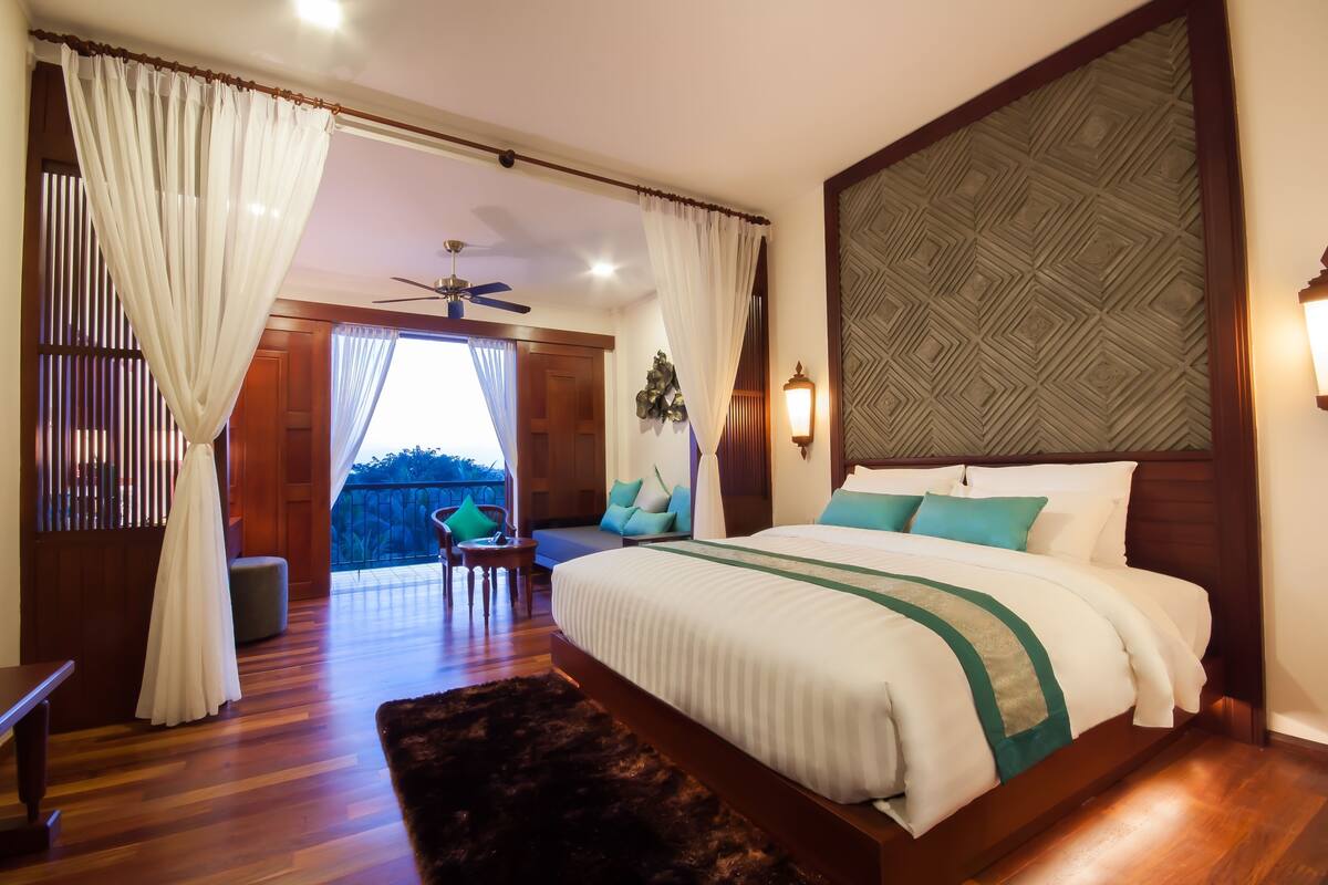 A spacious bedroom with a large bed, a ceiling fan, and a view of the outdoors.