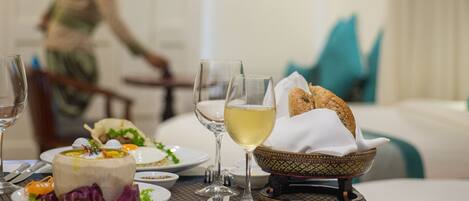 A dining table with plates of food, glasses of wine, and a bowl of bread.