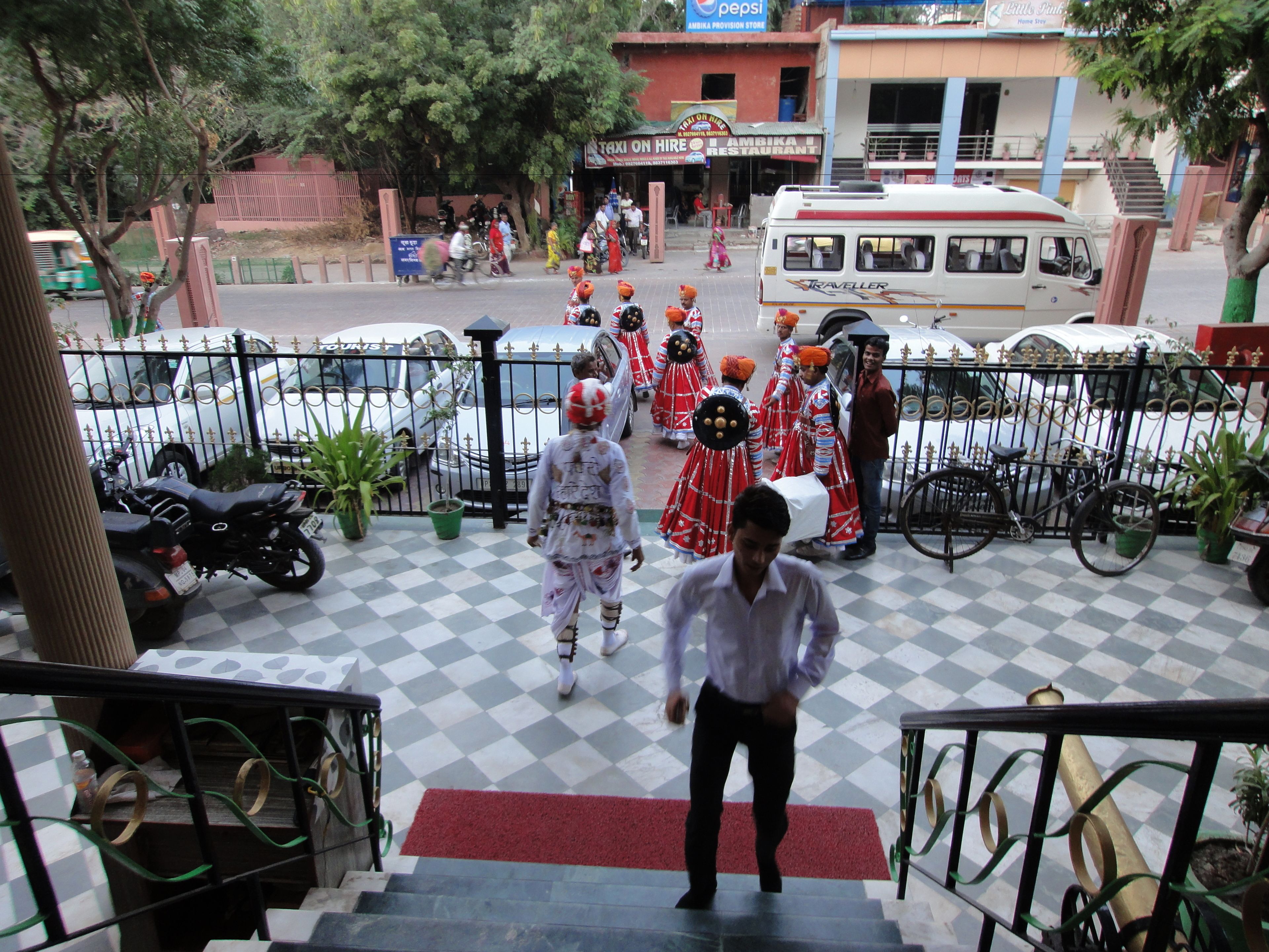 A hotel entrance with a checkered floor, a staircase, and a red carpet leading to the lobby.