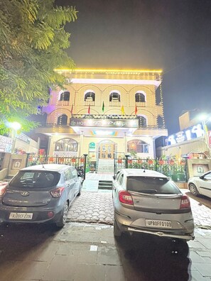 A hotel with a traditional facade, a central entrance, and a parking area with cars. - Hotel Taj Plaza (Agra)