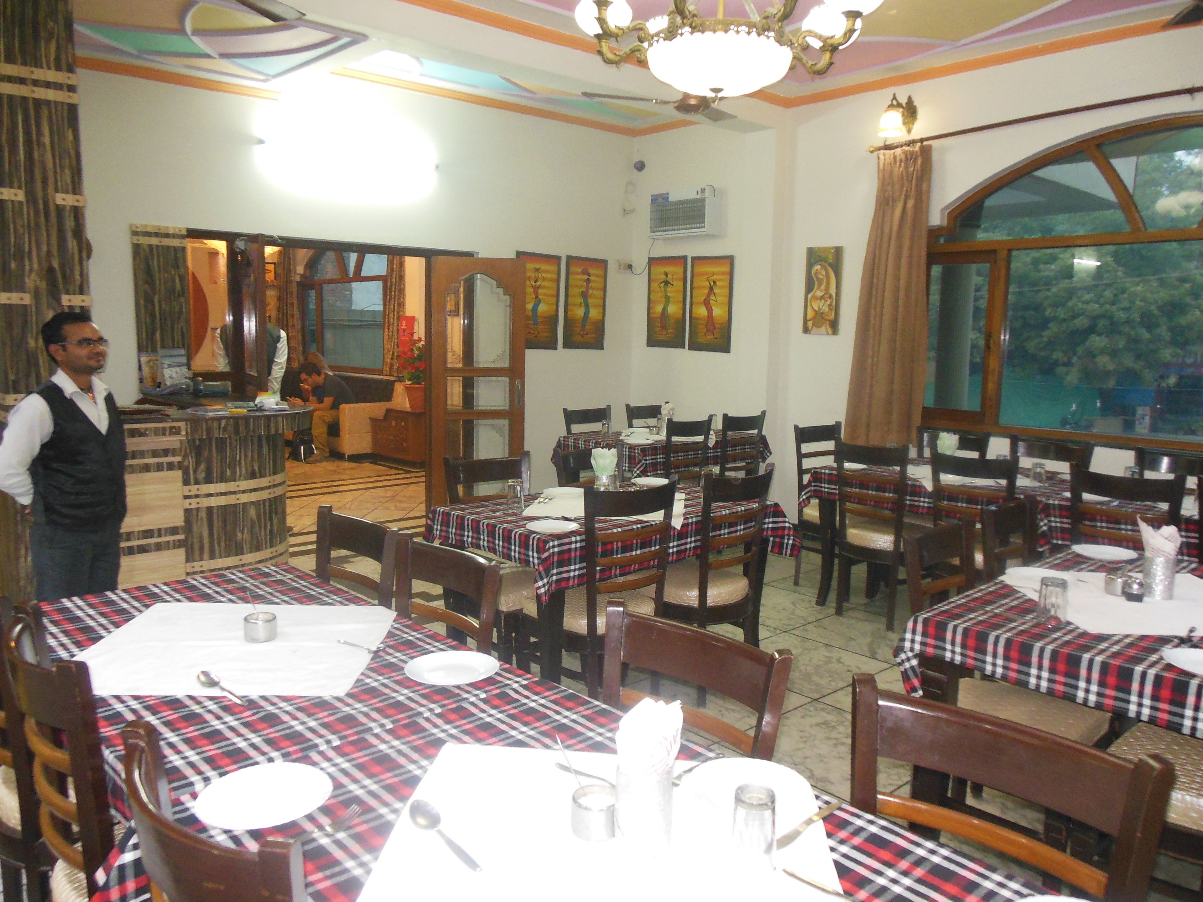 Un restaurante con varias mesas dispuestas para comer, sillas de madera y una zona de bar.