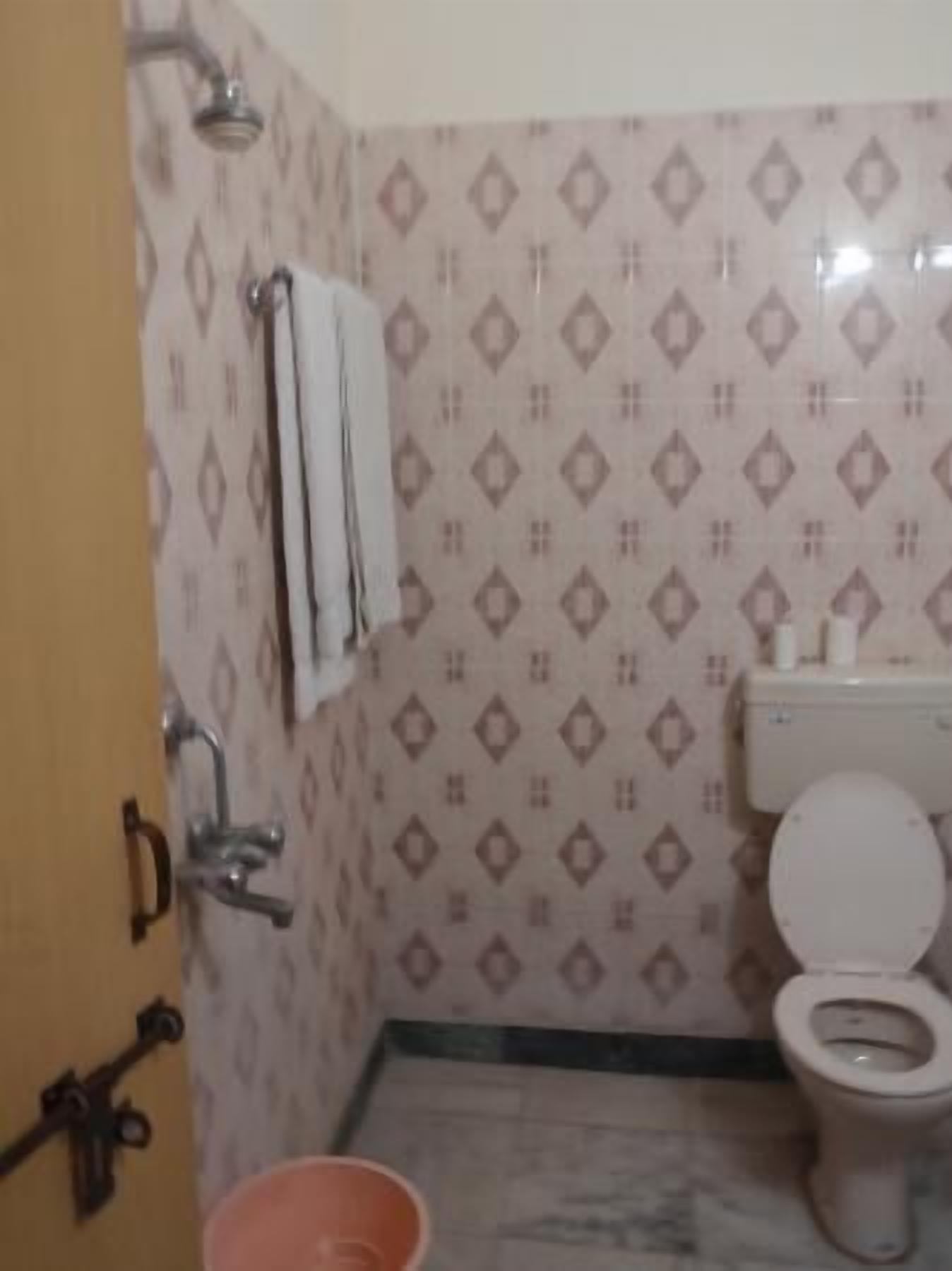 A bathroom with patterned tiles, a toilet, a shower, and a sink.